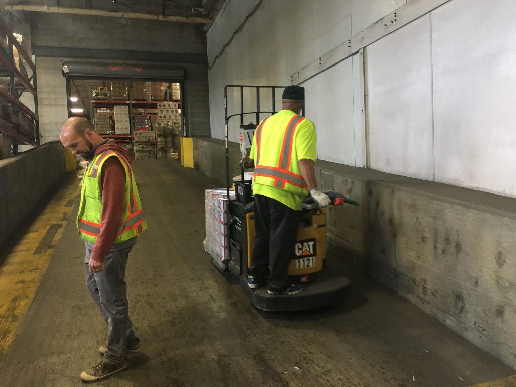 warehouse worker moving a pallet stacked with groceries