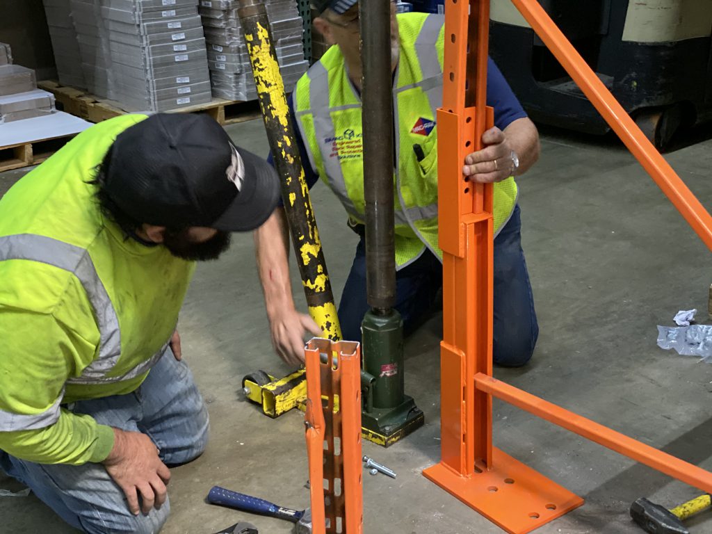 Rack repair kit is attached to pallet racking. The damaged section of the racking is moved to one side.