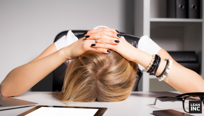 Sales manager frustrated with her head down on her desk